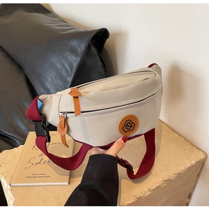 Detail of canvas chest bag featuring adjustable brown strap and premium leather logo patch