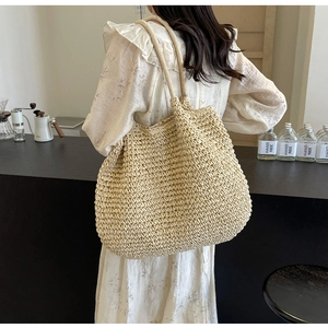 Gros plan sur un grand sac cabas en paille tressée beige avec une texture crochetée dense