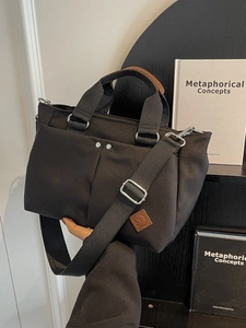 Versatile black canvas tote bag with adjustable wide strap and brown leather accents