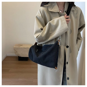 Detail of a black canvas crescent crossbody bag showing metal zip and leather strap attachment