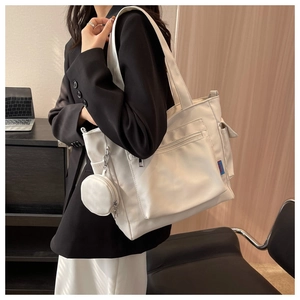 Detailed view of a white Oxford tote bag with a small round pouch in an office setting