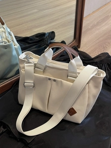 Versatile off-white canvas tote bag with brown leather handles and adjustable strap