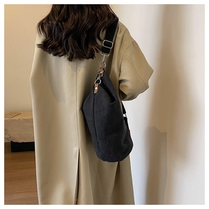 Detail of minimalist black canvas crossbody bag with wide strap on khaki trench coat