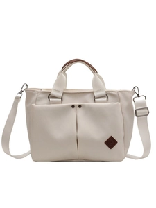 Versatile cream canvas tote bag with brown leather handles and adjustable shoulder strap