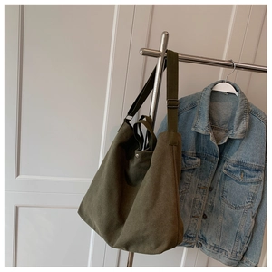 Vue détaillée du sac en toile vert olive avec bouton pression et large bandoulière
