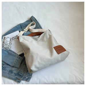 Detail of minimalist canvas bag with brown leather handles and adjustable shoulder strap