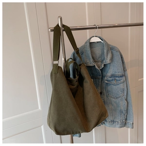 Détail du sac fourre-tout en toile vert olive avec bandoulière sur un cintre en métal