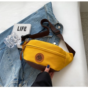 Detail of yellow canvas waist bag with leather logo patch and brown woven strap