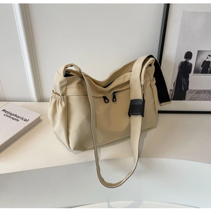 Détail d'un sac bandoulière en toile beige avec sangle réglable et poche latérale à cordon