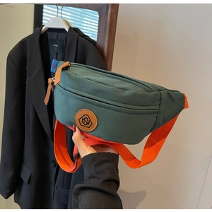 Detail of dark green canvas crossbody bag with bright orange adjustable strap and logo