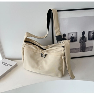 Détail du sac en toile beige avec bandoulière noire réglable et poche latérale à cordon
