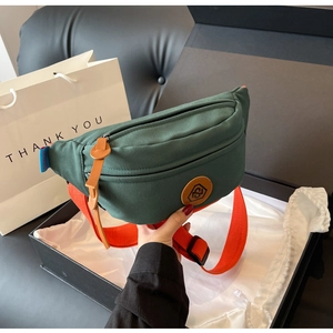 Detail of dark green canvas waist bag featuring a vibrant orange nylon strap and leather logo