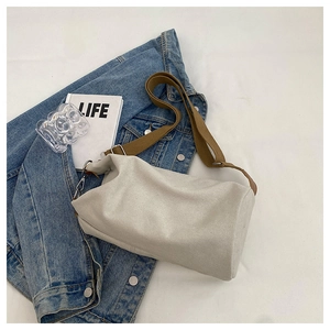 Detail of a beige canvas barrel bag with brown shoulder strap and silver metal hooks