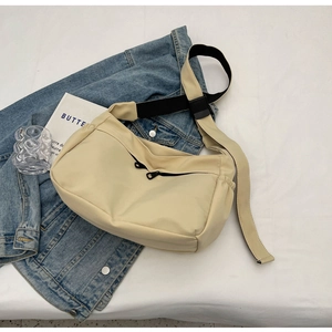 Détail d'un sac bandoulière en nylon beige avec sangle réglable et poches zippées