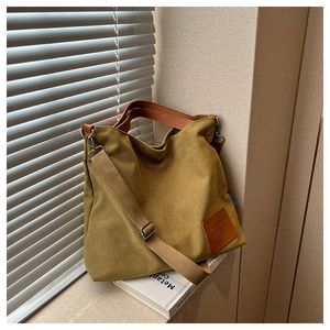 Close-up of mustard yellow canvas tote bag with leather handles and textured fabric strap