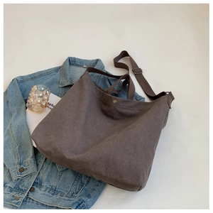 Vue à plat d'un grand sac cabas en toile marron avec bandoulière réglable et style rétro