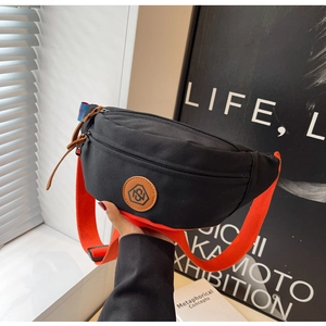 Close-up of black canvas chest bag with vibrant orange strap and hexagon logo patch