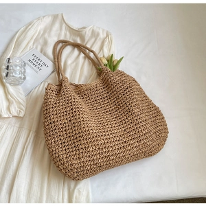 Dettaglio della grande borsa tote in paglia con trama intrecciata e robusti manici a spalla