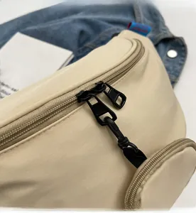 Detail of beige canvas chest bag with smooth black double metal zippers and woven pulls