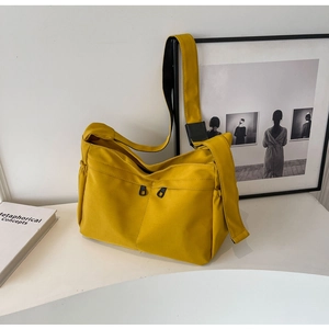 Détail d'un sac bandoulière en toile jaune avec double fermeture éclair et large sangle