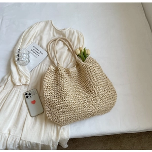 Dettaglio della borsa tote in paglia beige intrecciata con manici in corda spessa
