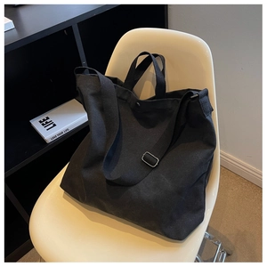 Vue détaillée du sac en toile noire avec sangle réglable et bouton-pression métallique
