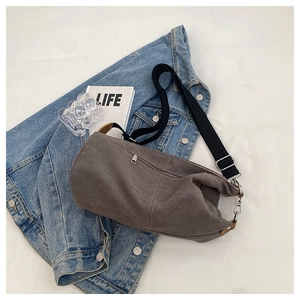 Detail of grey canvas crossbody bag with black nylon strap on denim jacket outfit