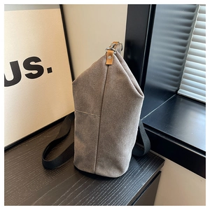 Detail view of khaki canvas bucket bag with black strap and brown leather accents