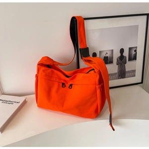 Détail du sac fourre-tout en toile orange vif montrant les fermetures éclair et poches