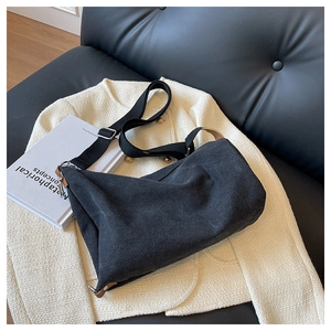 Close-up of black canvas crescent bag with leather trim on white tweed texture