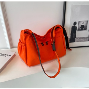 Vue détaillée du sac cabas en toile orange vif montrant la poche latérale et la sangle