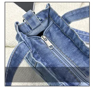 Detail view of smooth metal zipper and reinforced stitching on dark denim tote bag