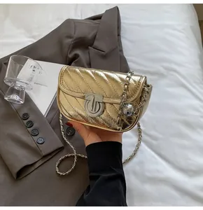 Detail of gold quilted chain bag with round metal lock and woven leather strap