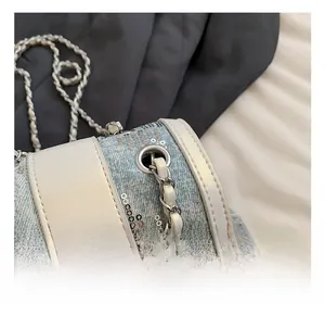 Close-up of silver sequins on blue denim barrel bag with elegant metal chain strap
