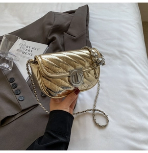 Detail of golden quilted bag featuring a silver twist lock and chic metal ball chain strap