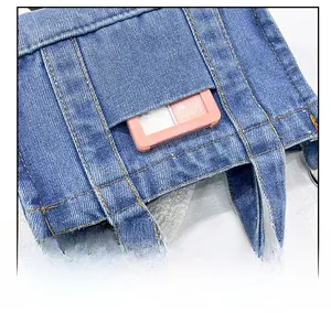Detail of blue denim crossbody bag featuring a functional front pocket with neat stitching