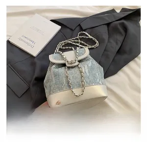 Detail of blue sequin bucket backpack with white leather trim and metal chain strap