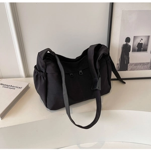 Détail du sac bandoulière en toile noire avec doubles zips et poches à cordon latérales