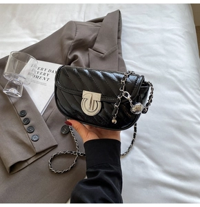 Detailed view of glossy black V-quilted small square bag with silver rotary lock and chain