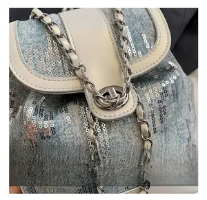 Close-up of silver metal twist lock and sequins on a light blue denim style bag