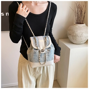 Side view of a sequined denim bucket backpack with chain straps on a female model