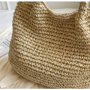 Gros plan sur la texture tissée dense d'un sac cabas en paille beige avec détails déco