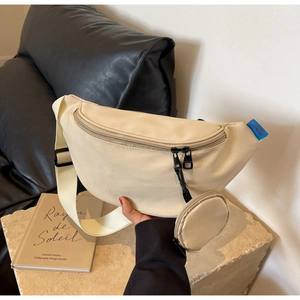 Detail of beige canvas crossbody bag featuring a wide strap and small round coin purse