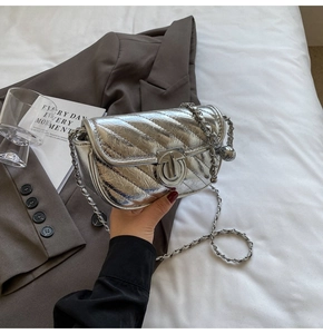 Detail of silver metallic crossbody bag featuring quilted stitching and chain strap