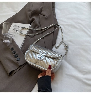 Detail of silver metallic quilted crossbody bag with stylish metal lock and chain strap