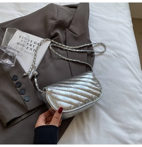 Close-up of a silver quilted crossbody bag with a metal chain strap and flap closure