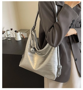 Detail of silver metallic tote bag with adjustable strap and iconic triangle metal plate