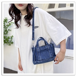 Detailed close-up of blue washed denim tote bag with silver hardware and sturdy stitching