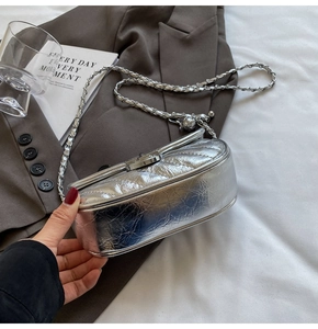 Detail view of silver quilted chain bag with metallic finish on gray suit blazer