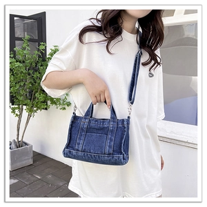 Detail of dark blue denim tote bag with yellow stitching and detachable shoulder strap